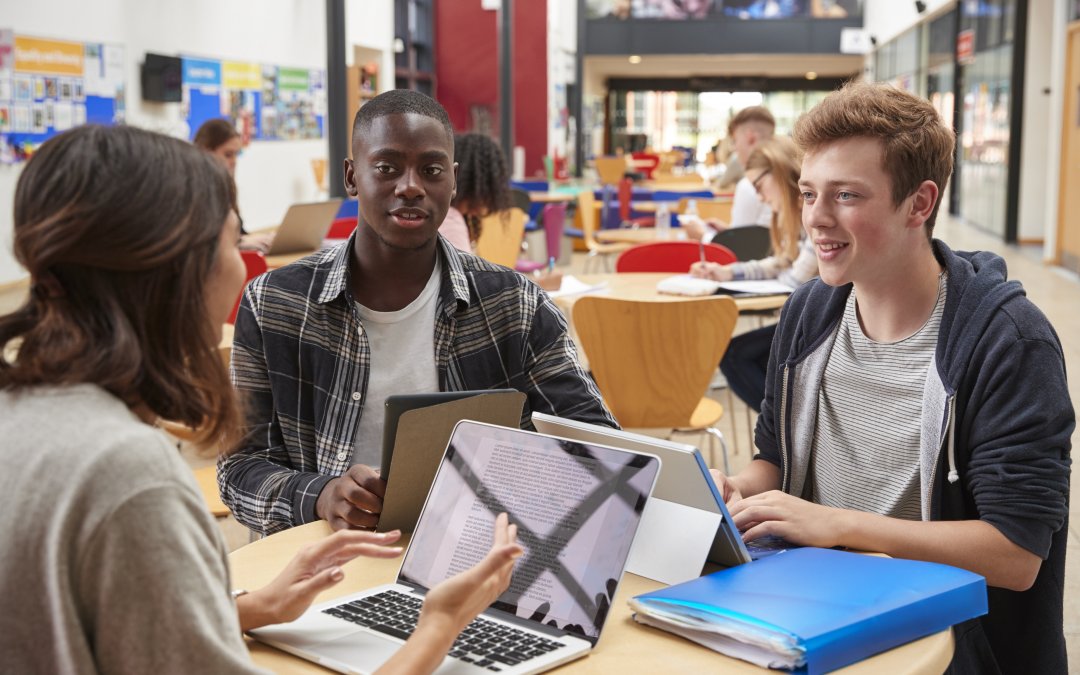 Teacher Talks To Students In Communal Area of College Campus